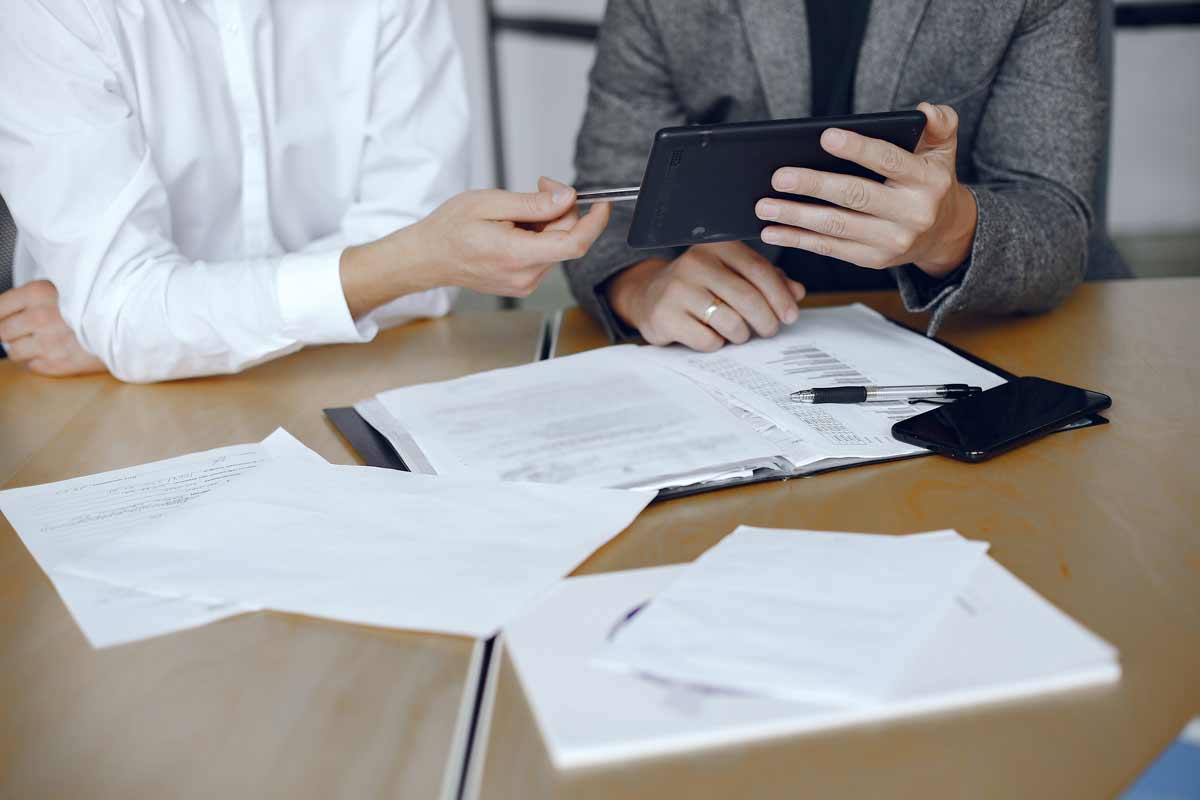 Hombres sentados firmando documentos.